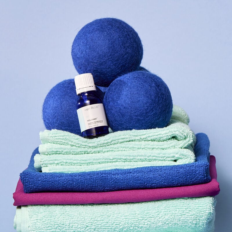 Volcano Laundry Fragrance Oil on a stack of laundry with dryer balls image number 2